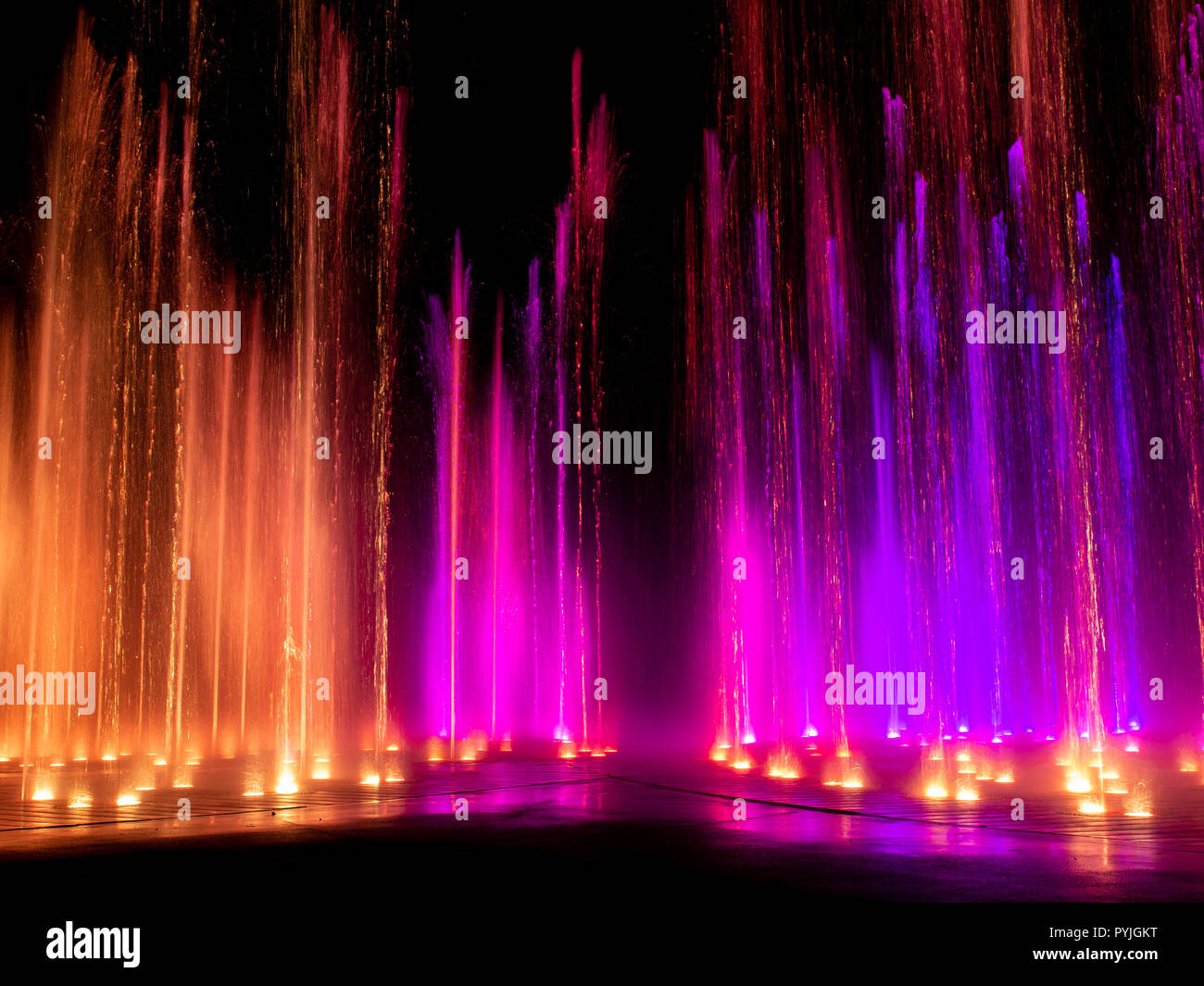 Large multi colored decorative dancing water jet led light fountain show at night Stock Photo