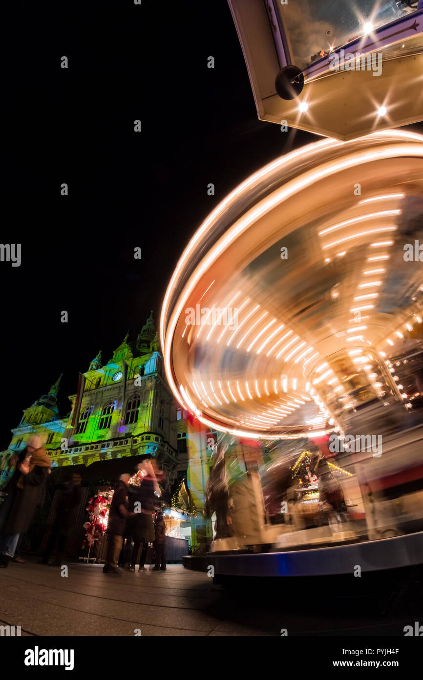 Spinning carousel on christmas fair on main square in Graz with town hall Stock Photo