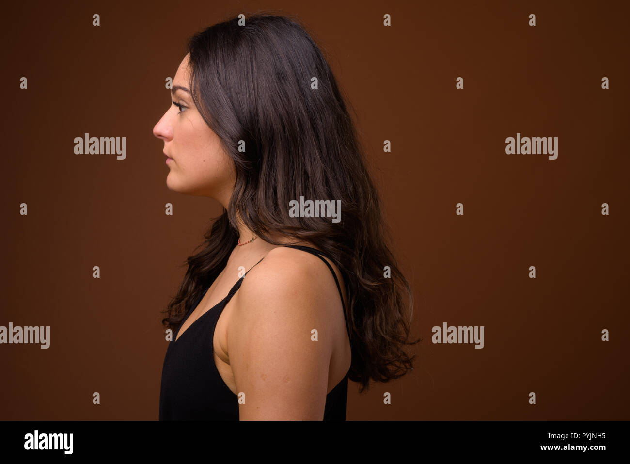Studio shot of young beautiful woman against brown background Stock ...