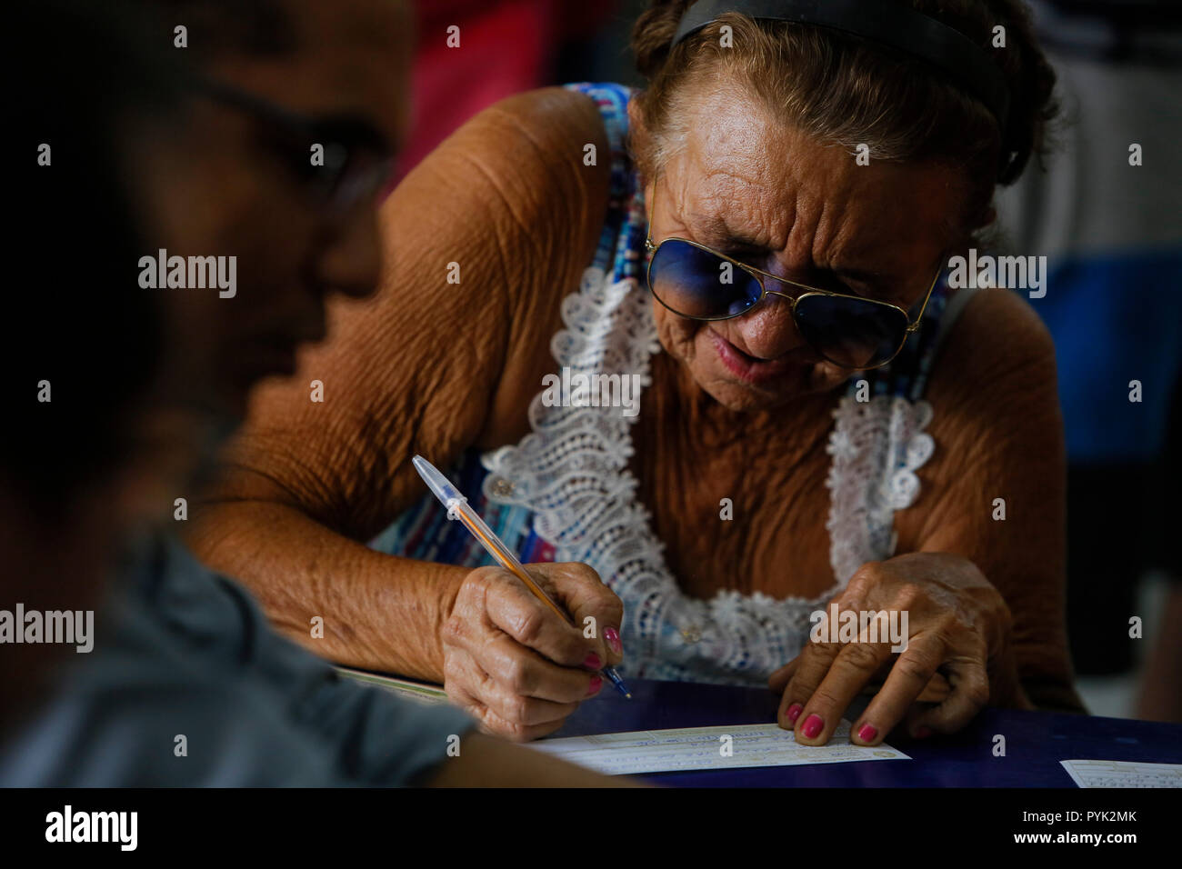 Recife, Brazil. 28th Oct, 2018. A woman who can't vote signing a petition at a polling station. The favourite in the run-off was right-wing populist Bolsonaro, who repeatedly insults minorities and provokes them with extremist slogans. 'Democracy is at stake today,' said counter-candidate Haddad of the Left Workers Party after the vote in Sao Paulo. Credit: Diego Herculano/dpa/Alamy Live News Stock Photo