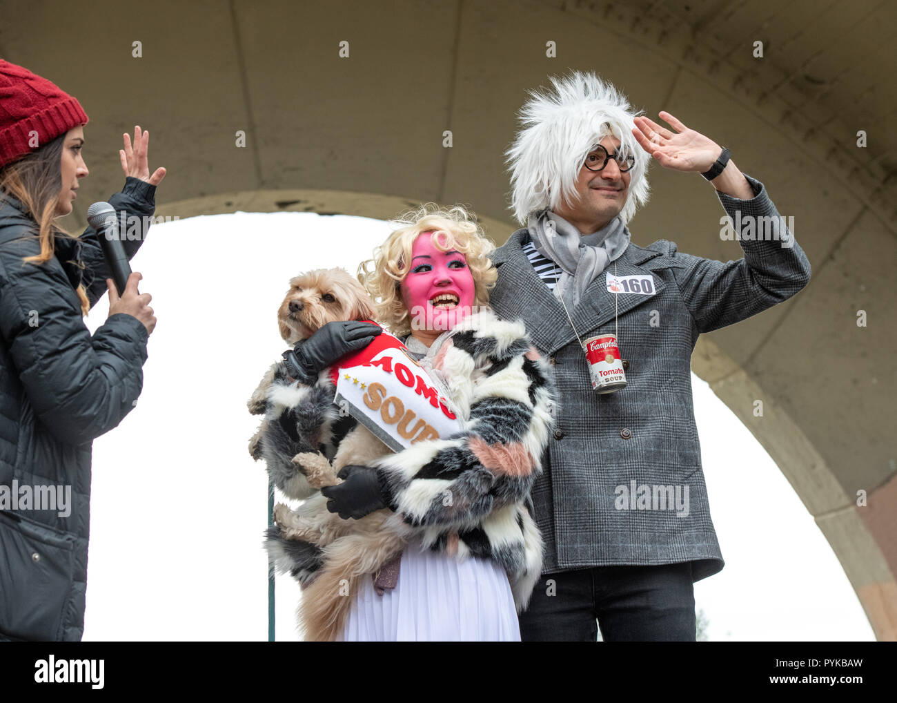 New York, USA,28 October 2018.  A dog wearing a Campbell Soup outfit with its owners dressed as Andy Warhol and Marilyn wave from the stage during the 28th Annual Tompkins Square Halloween dog parade in New York city. Credit: Enrique Shore/Alamy Live News Stock Photo