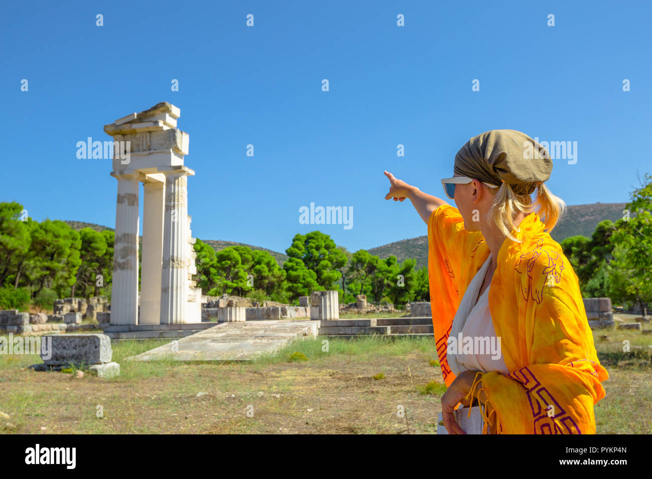 Greek dressed woman in indicates the ruins of Temple of Asklepieion, Epidaurus, Peloponnese, Greece. The Sanctuary of Asclepius is a famous heritage site.Mediterranean travel and tourism concept Stock Photo