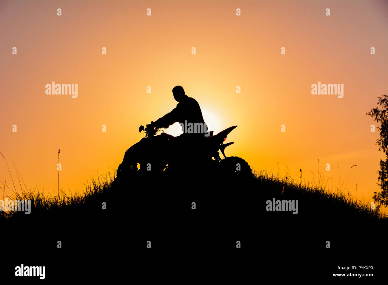 Silhouette of quad bike driver on the mountain / Силует квадроциклиста на горе в закатном свете Stock Photo
