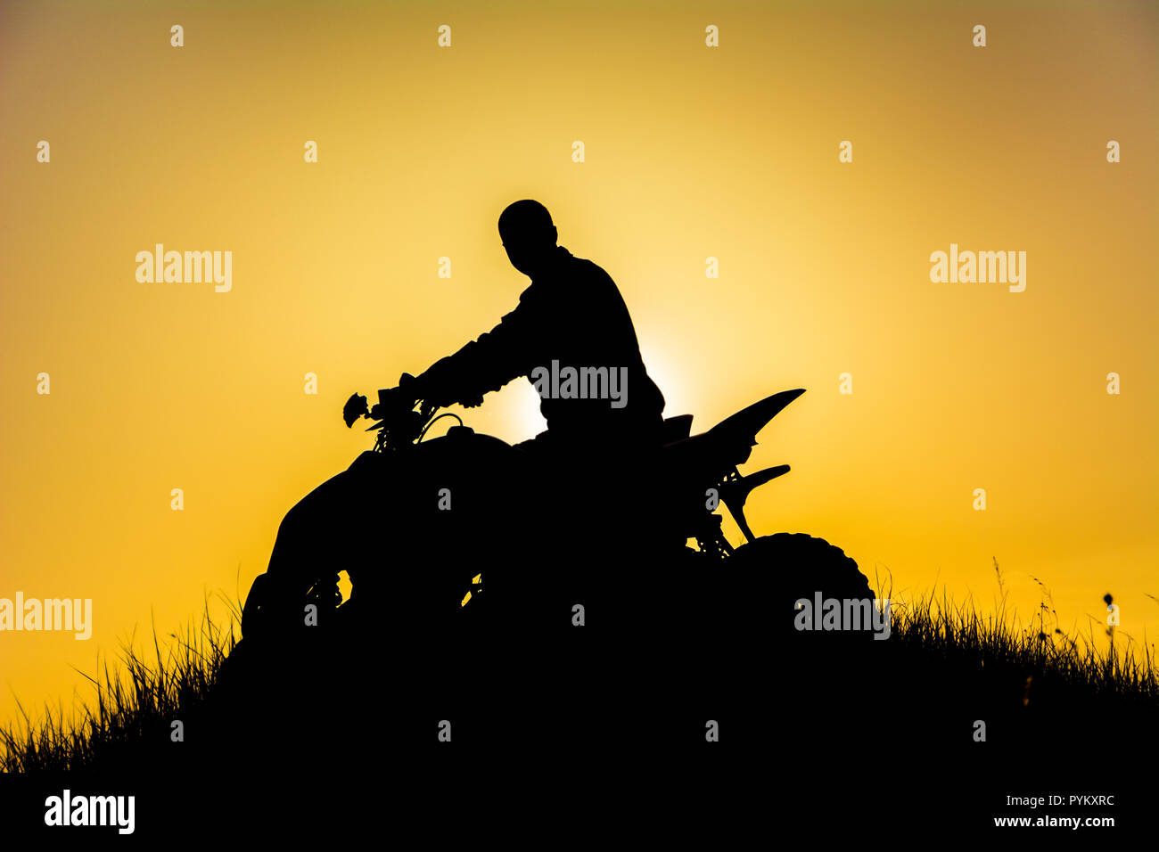 Silhouette of quad bike driver on the mountain / Силует квадроциклиста на горе в закатном свете Stock Photo