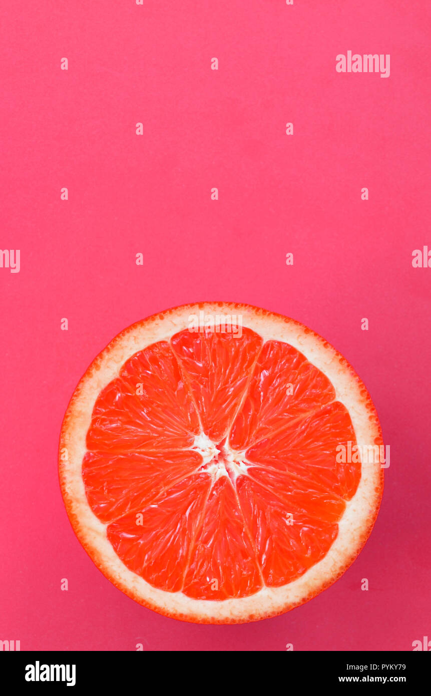 Top view of an one grapefruit slice on bright background in pink color. A saturated citrus texture image Stock Photo