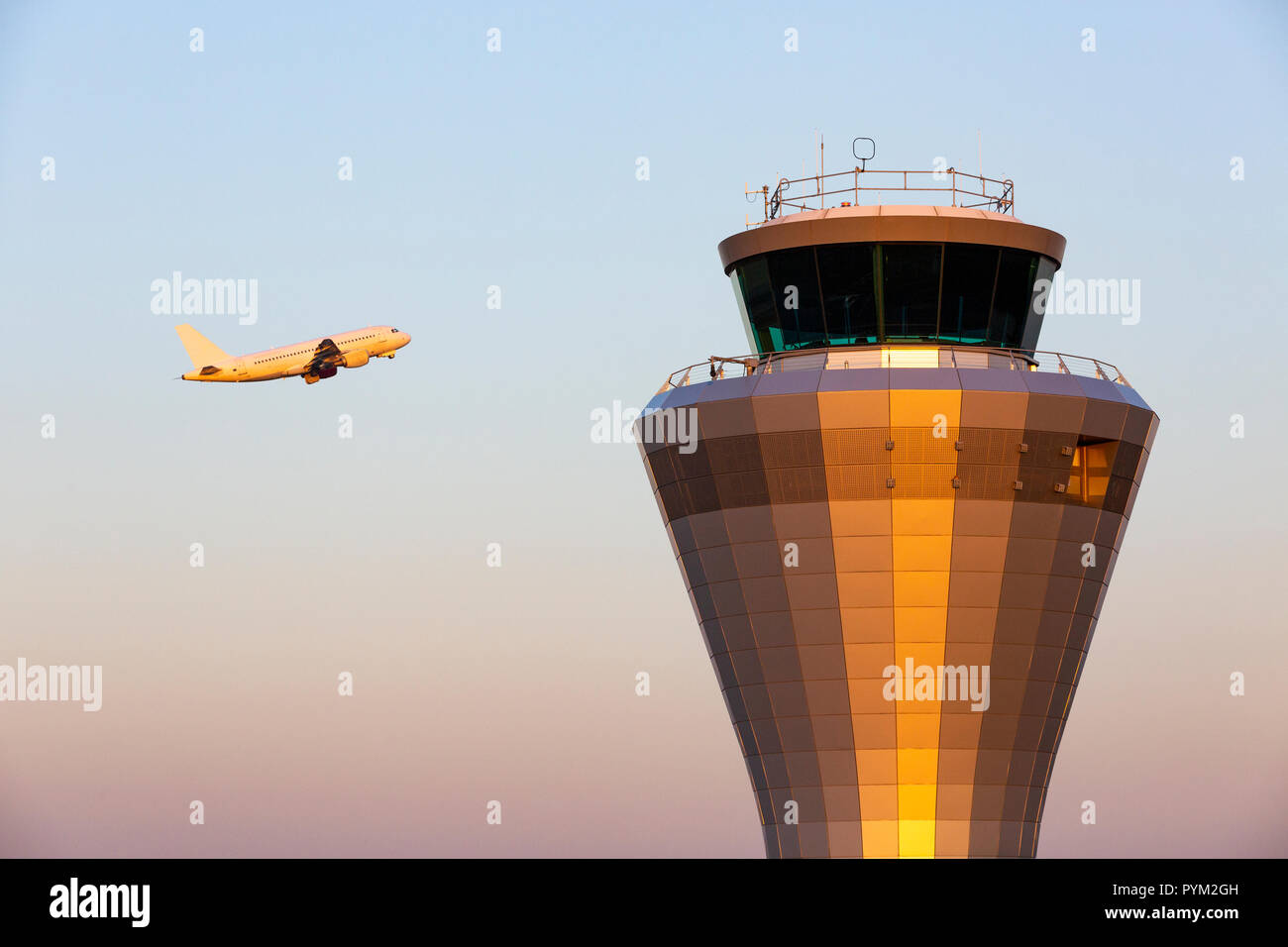 A jet aircraft flying past an air traffic control tower as it takes of at Birmingham Airport in England, UK Stock Photo