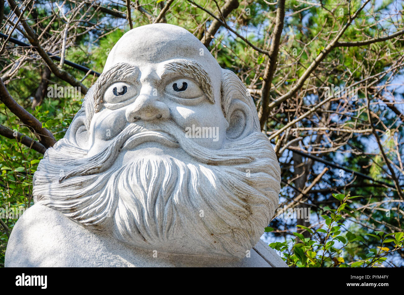 A stone statue of a bearded man wearing robes at Haedong Yonggung Temple in Busan, South Korea. Stock Photo
