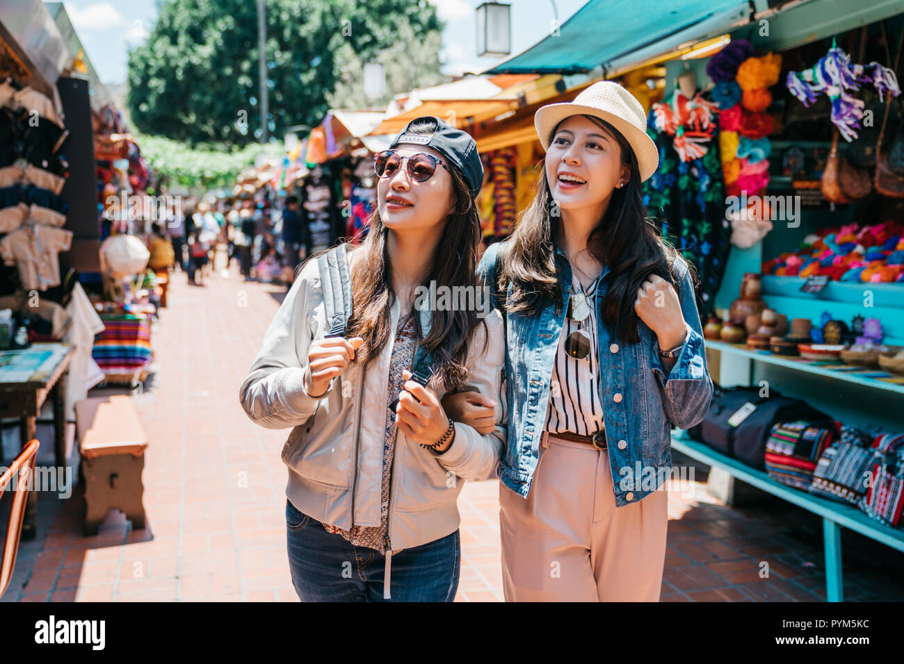 pretty backpackers cheerfully shopping in the Mexican street together. travelers visiting famous Mexico street in trip. summer holiday travel in Ameri Stock Photo