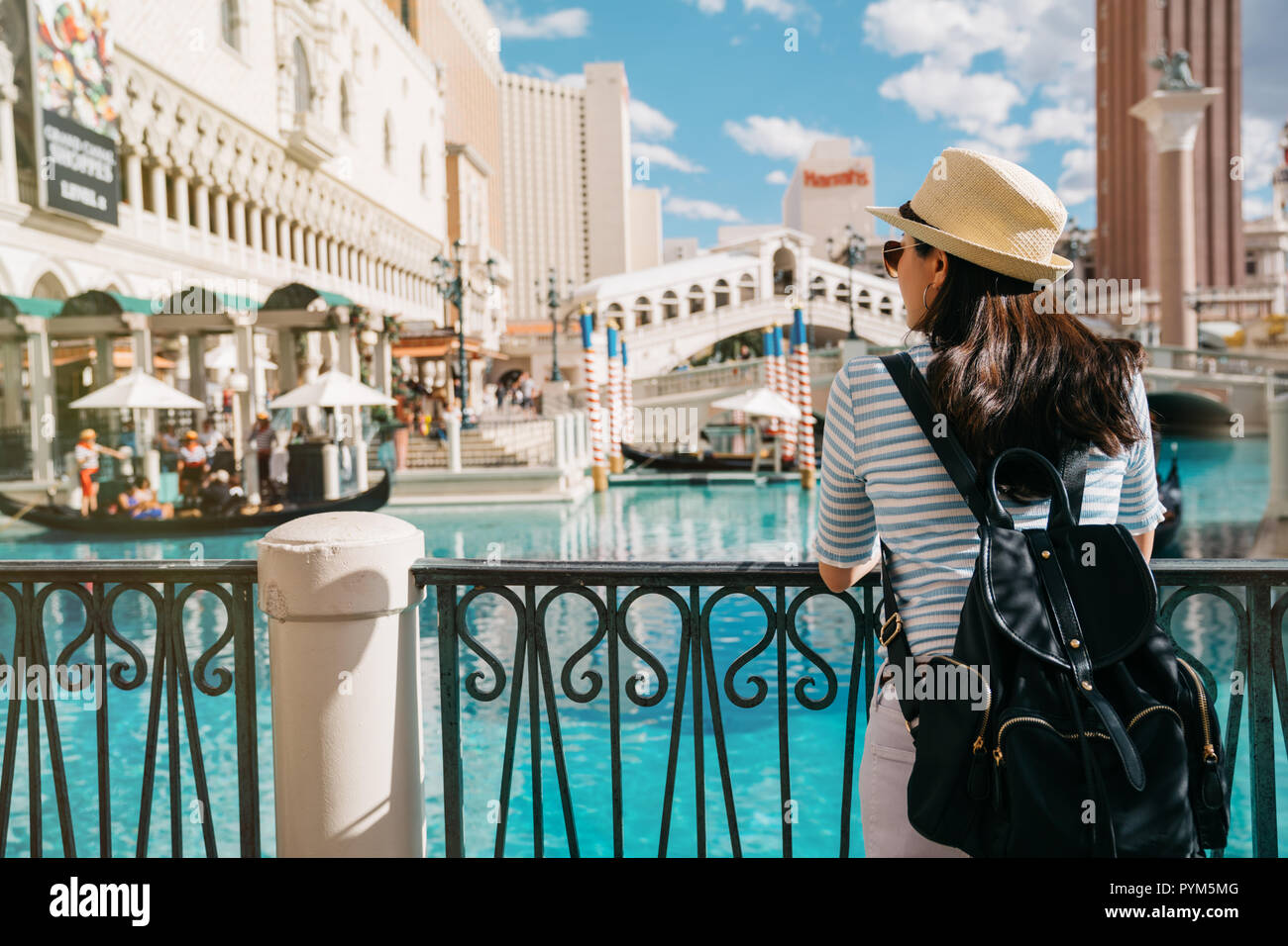 tourist visiting Venice and looking at the famous gondola cannal with people on the boat. back view of asian lady backpacker enjoying summer vacation. Stock Photo