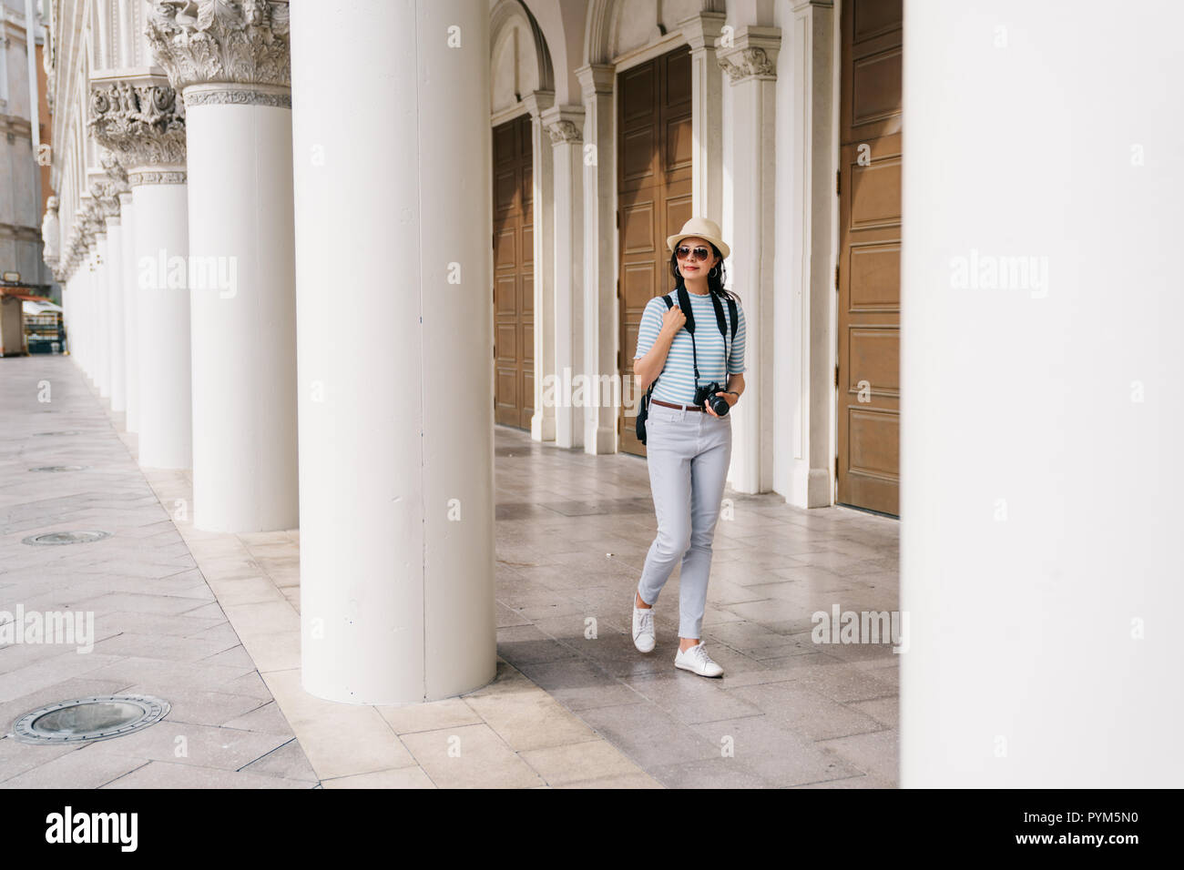 full length photo of a beautiful lady walking in the corridor of the Greek style building. Asian tourist visit famous monument in city center in Las v Stock Photo
