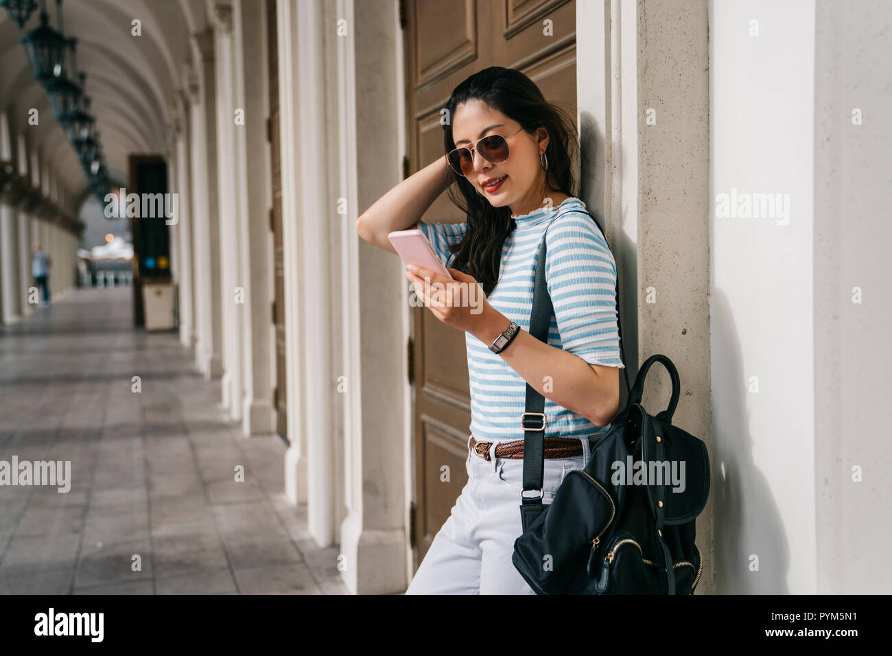 pretty college girl waiting her friend on the passageway after the course. Student lady outdoor in balcony smiling happy going back to home. teenager  Stock Photo
