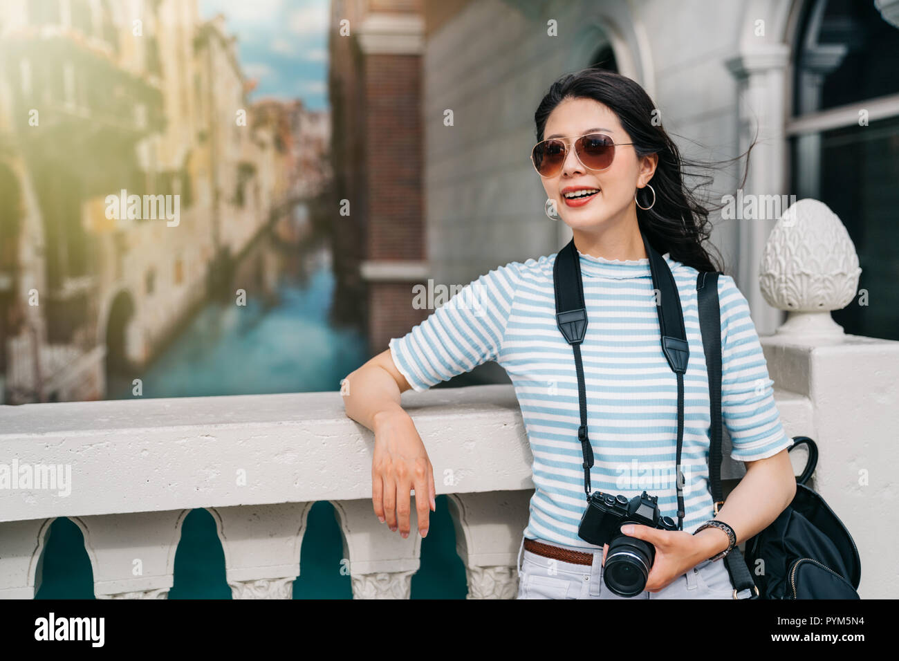 beautiful photographer traveling in Europe and relaxing on the bridge. travel lens man having trip in Italy concept. young Asian lady enjoying holiday Stock Photo