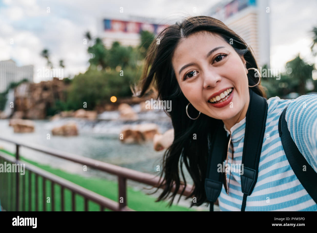 cute lady taking selfie in front of the pond in the park in America. young girl independent travel in las vegas. woman taking self portrairt photo con Stock Photo