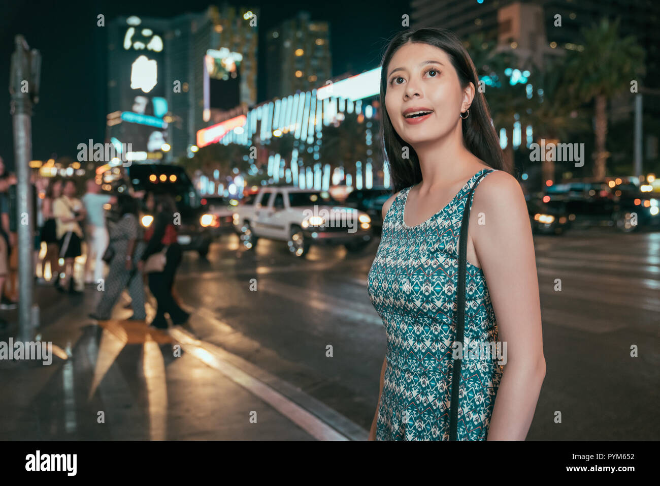 asian young girl night out to club walking on the road in dark urban. elegant woman in dress looking at the tall skyscraper in the city. teenager in l Stock Photo