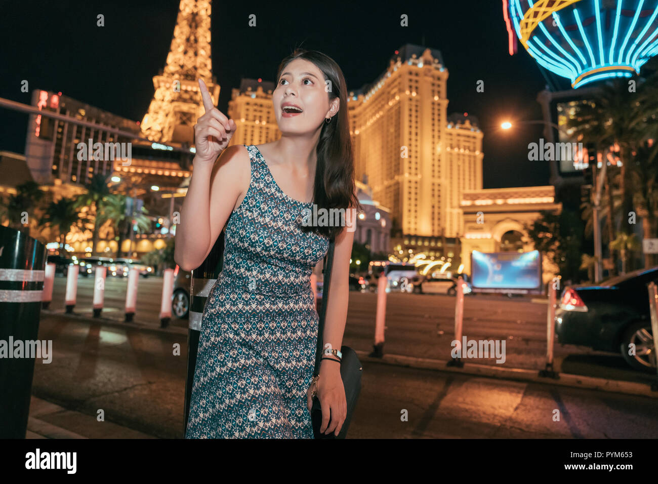 travel asian woman enjoying the beauty of the dark sky at night in las vegas. Joyful lady standing in the city center pointing to the black sky with m Stock Photo