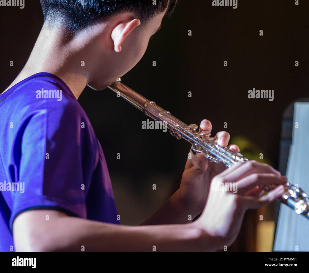 Back view of  a male musician student practicing playing flute at school Stock Photo