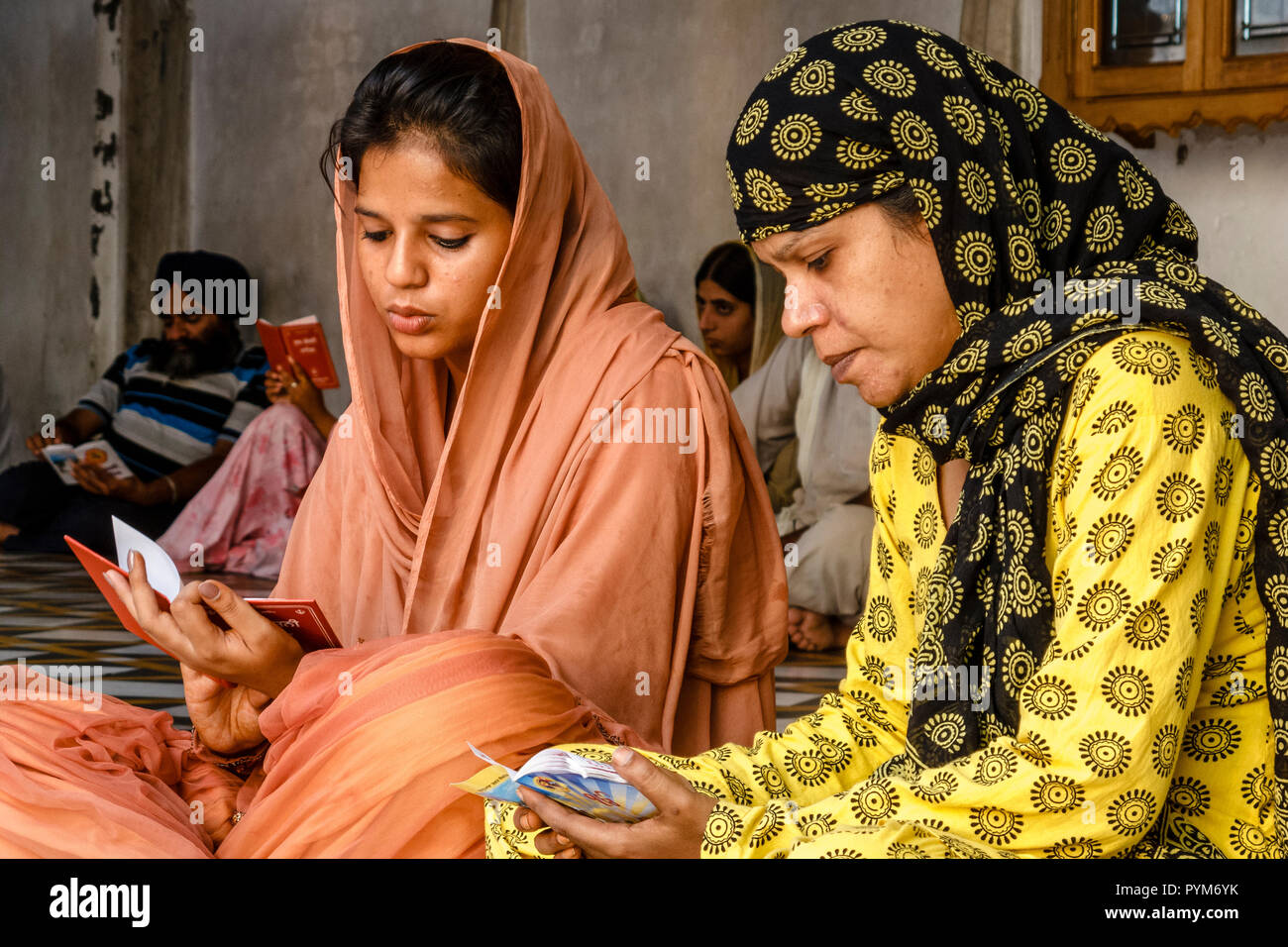2 Sikh ladies reciting texts from the holy scriptures Stock Photo