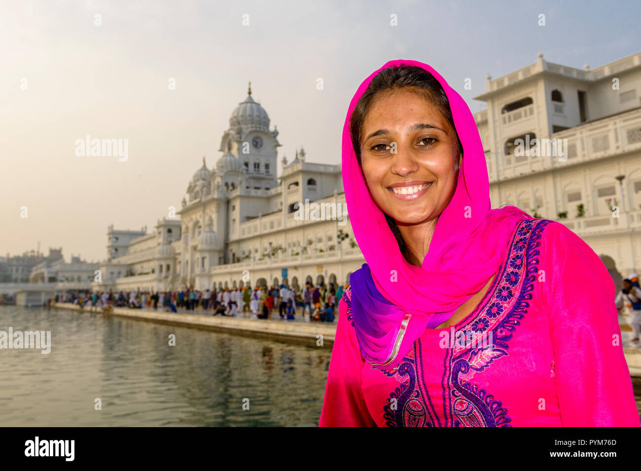 A portrait of a smiling young female Sikh devotee, dressed in red ...