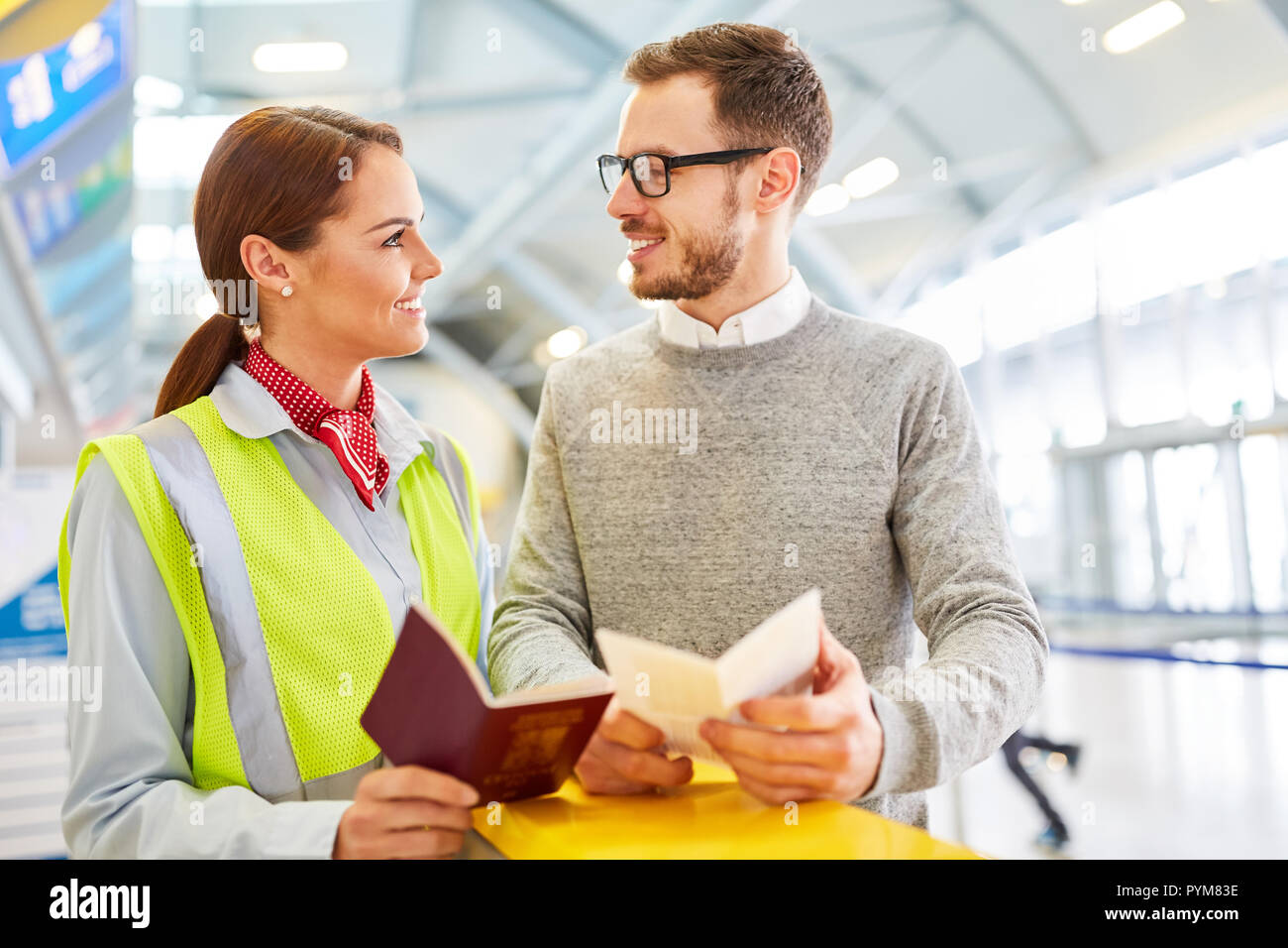 Service clerk and passenger with travel documents at the airport check-in counter Stock Photo