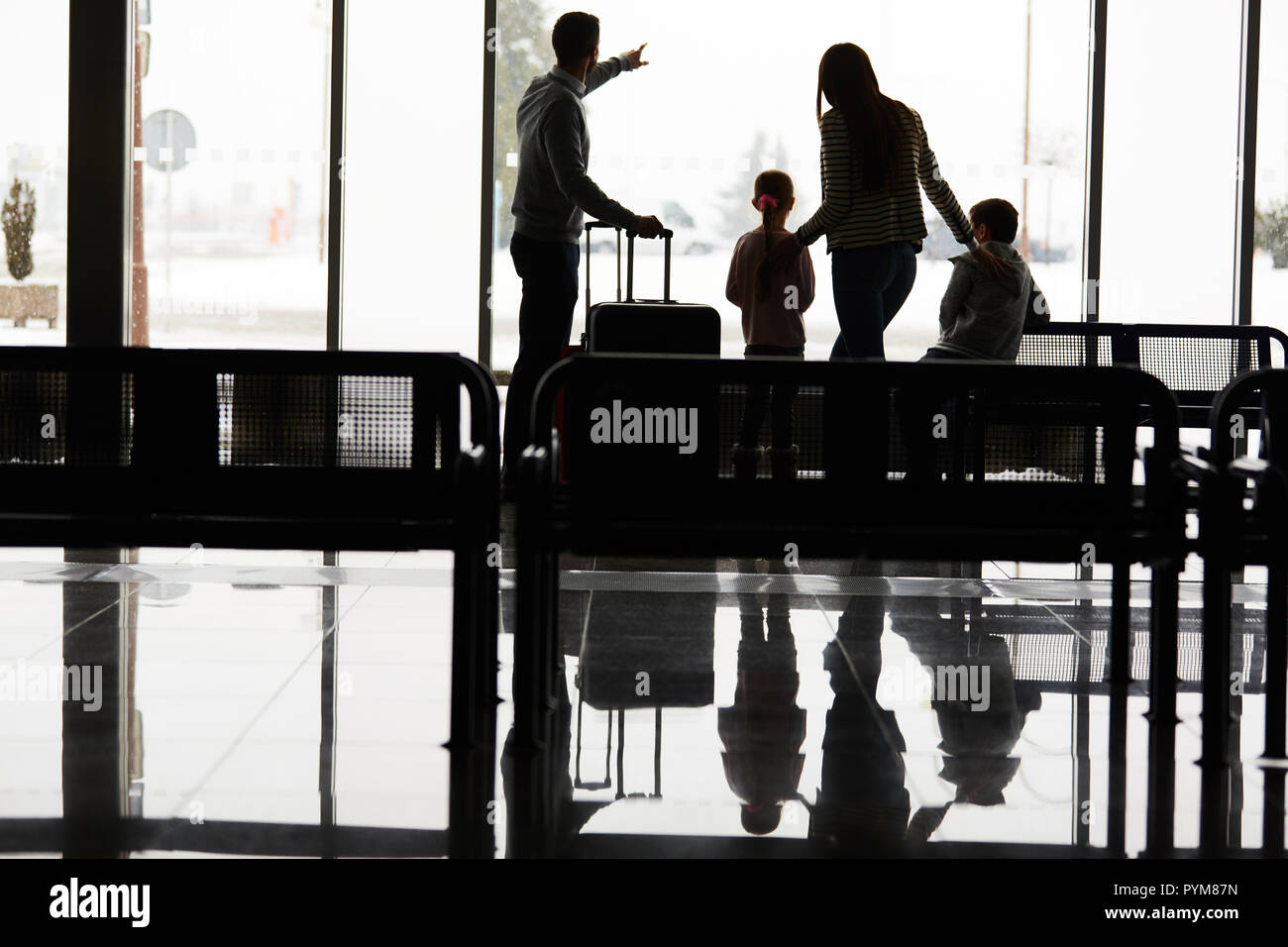Family and children in the airport terminal wait together for the departure on vacation Stock Photo