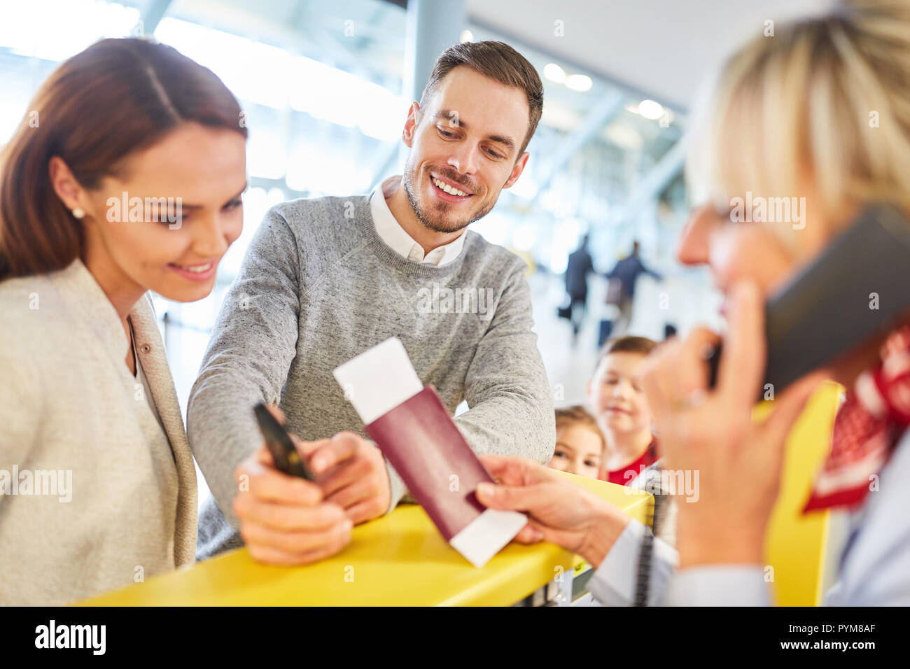 Service Agent checks passport and family documents at the check-in counter Stock Photo
