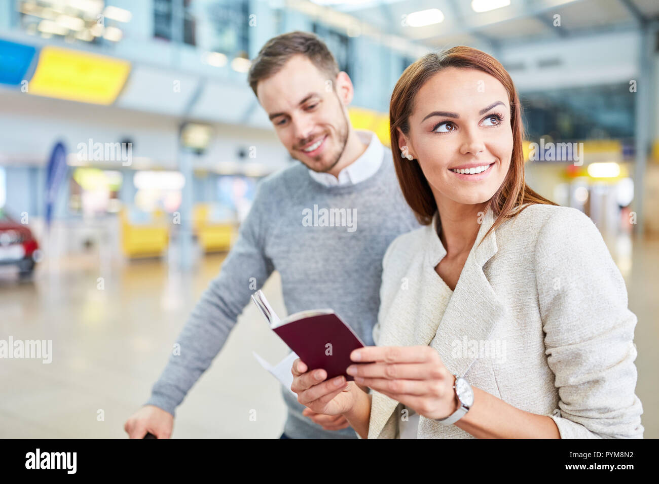 Young couple in the airport terminal with travel documents waiting for the connecting flight Stock Photo