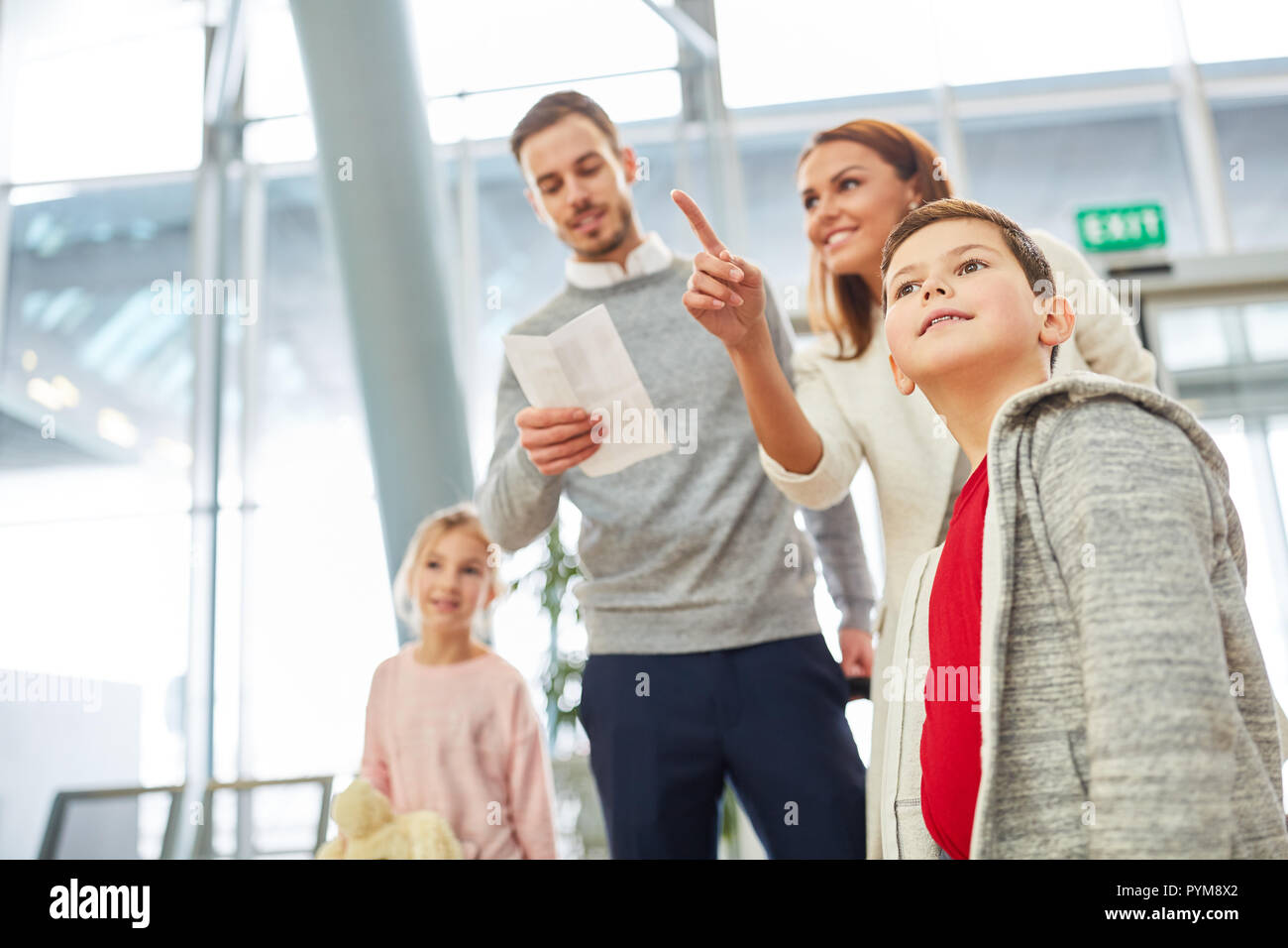 Happy family and two children eagerly look for the right gate in the airport terminal Stock Photo