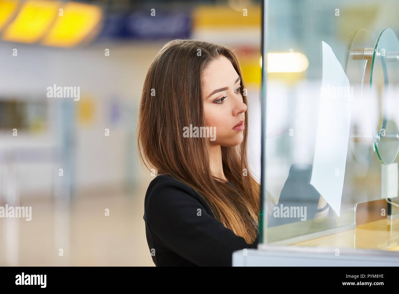 Woman as a passenger at the check-in desk in the airport terminal fills out a form Stock Photo