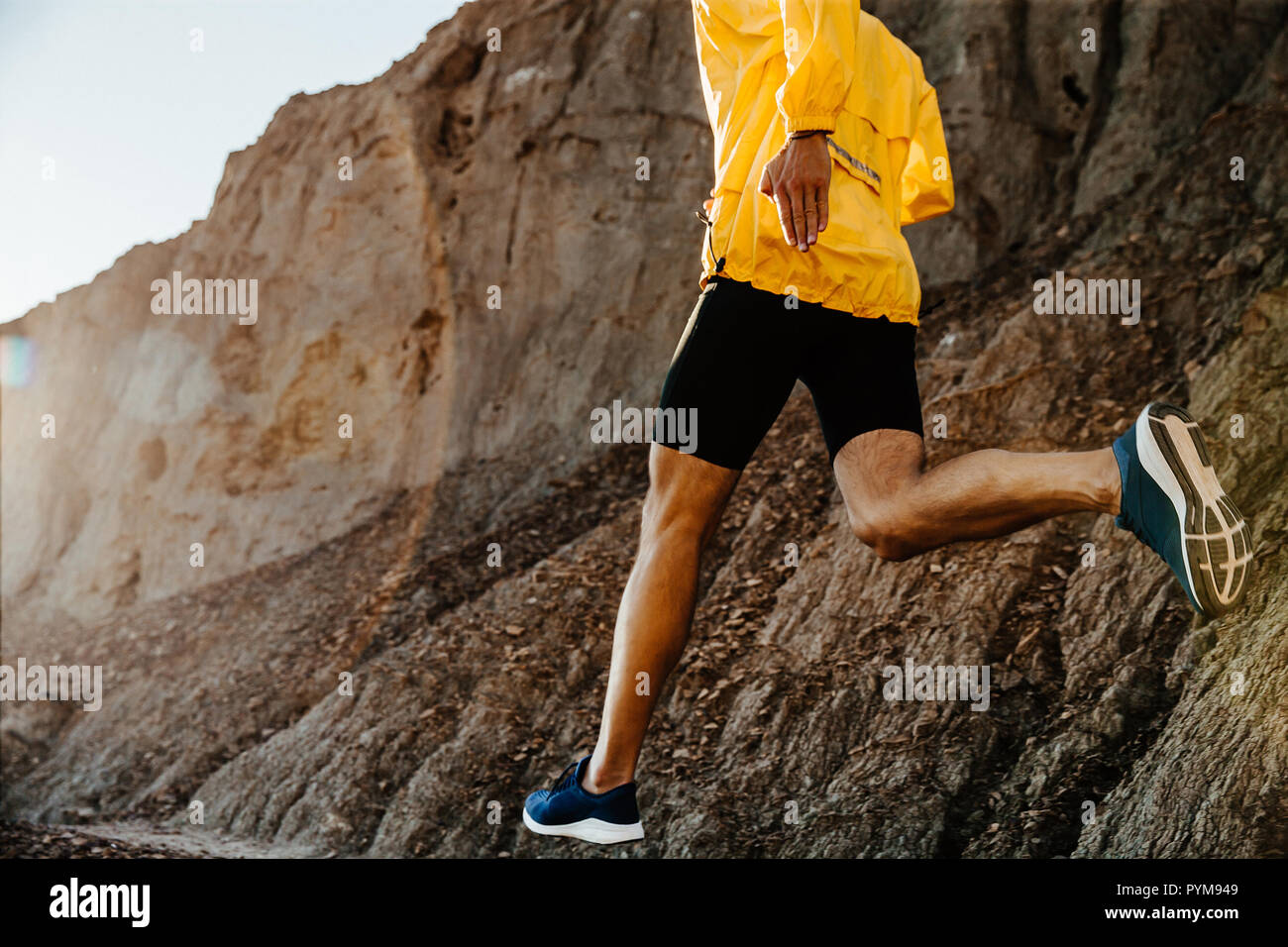 healthy lifestyle sports man running on mountain trail in sunlight Stock Photo
