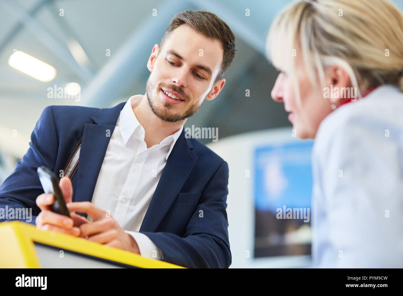Businessman as a passenger with smartphone at the online check-in counter in the airport Stock Photo