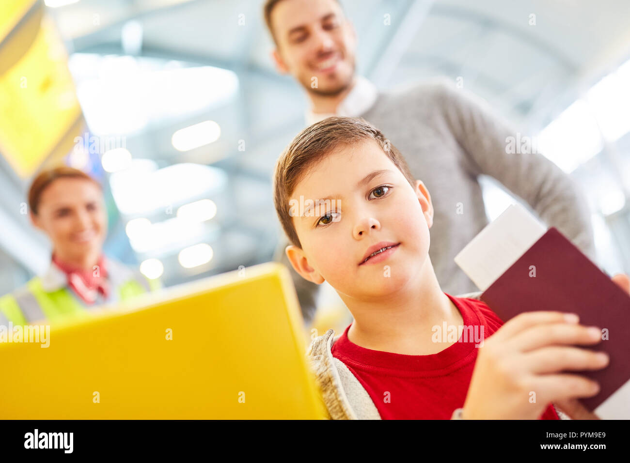Boy with passport at check in counter in airport terminal with father ...