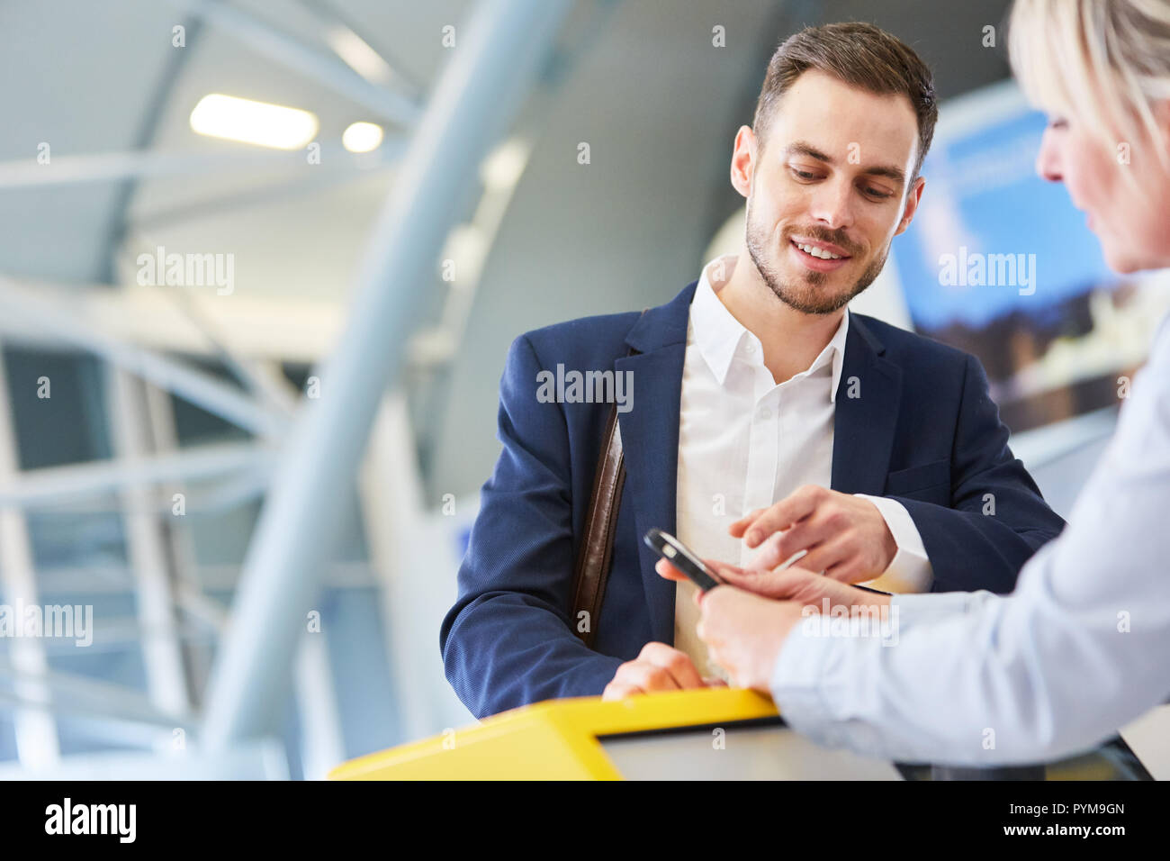 Businessman using smartphone at check in or baggage drop off counter in airport Stock Photo