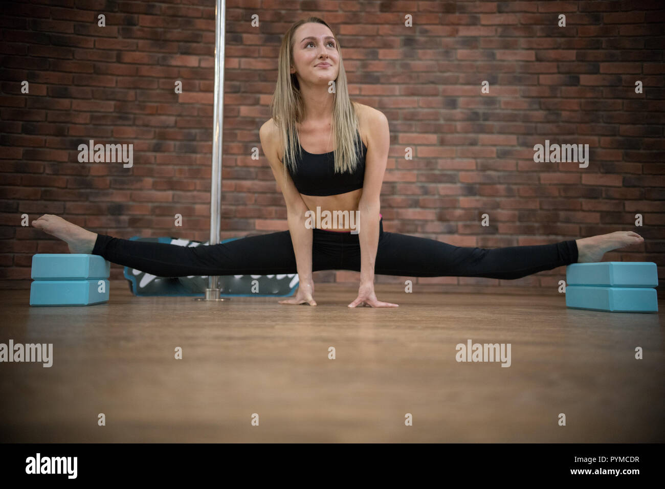 Young beatiful woman doing the splits in pole dance studio Stock Photo