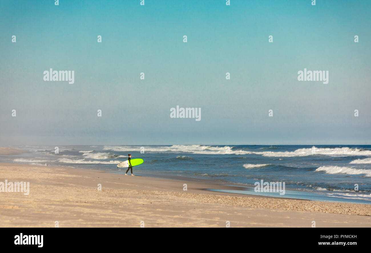 person with a bright green surf board at an eastern long beach Stock Photo