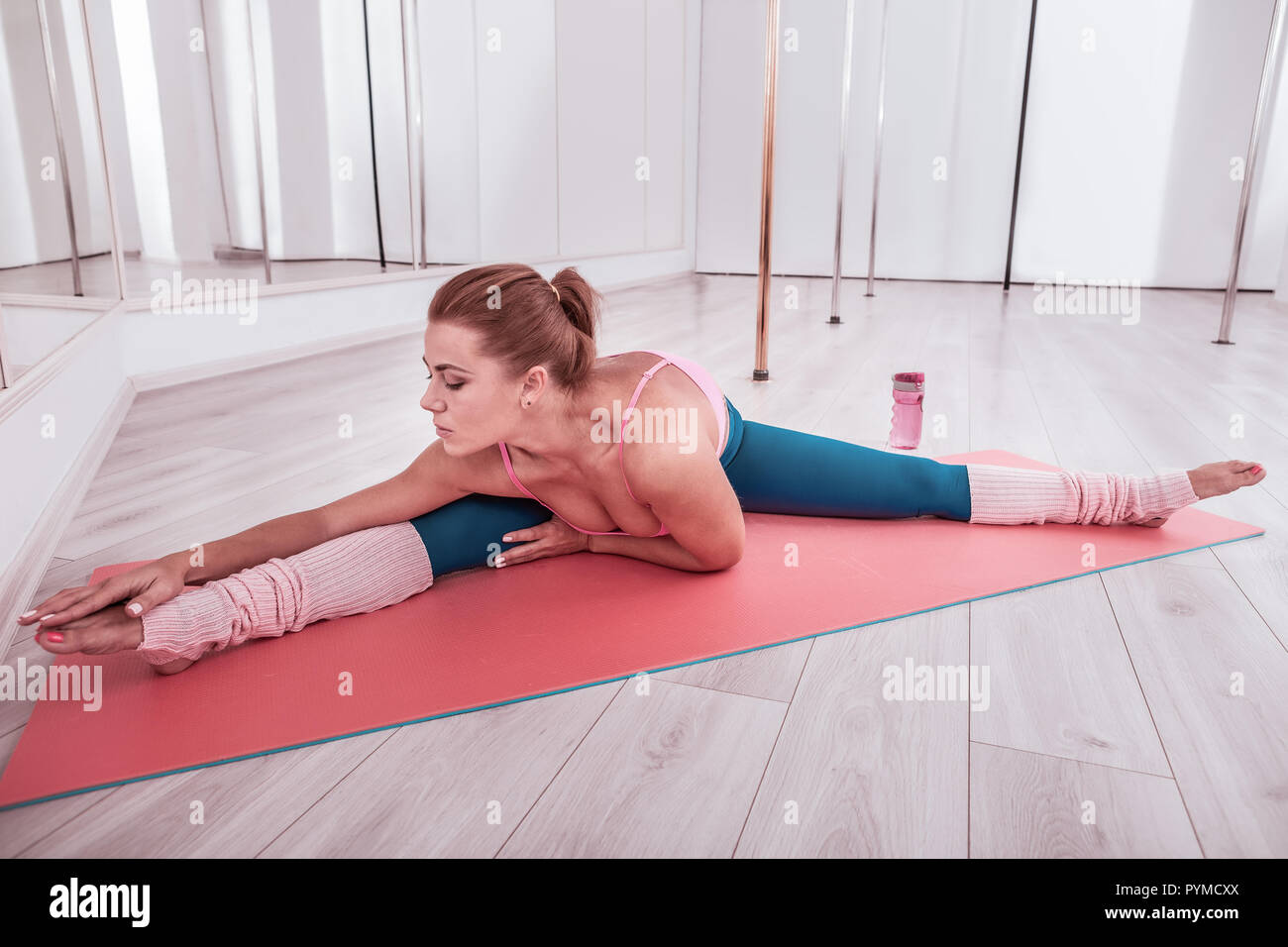 Red-haired slim and fit woman wearing comfy leggings stretching her body  Stock Photo - Alamy