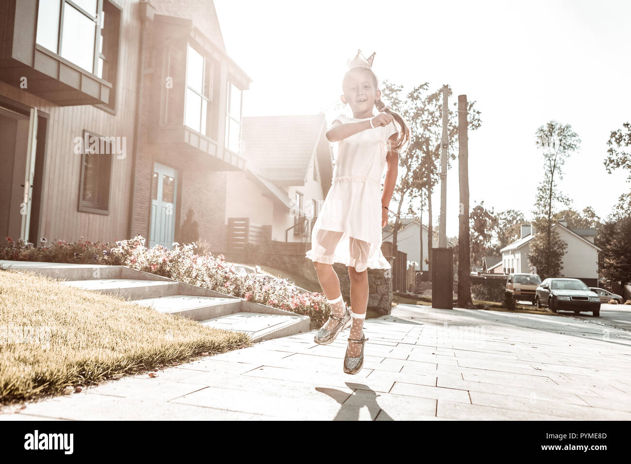 Beautiful dark-haired girl wearing little crown walking near her house Stock Photo