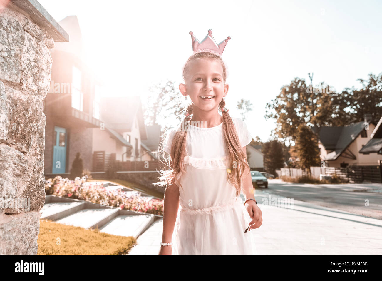 Beaming cheerful dark-haired girl wearing little crown feeling happy Stock Photo