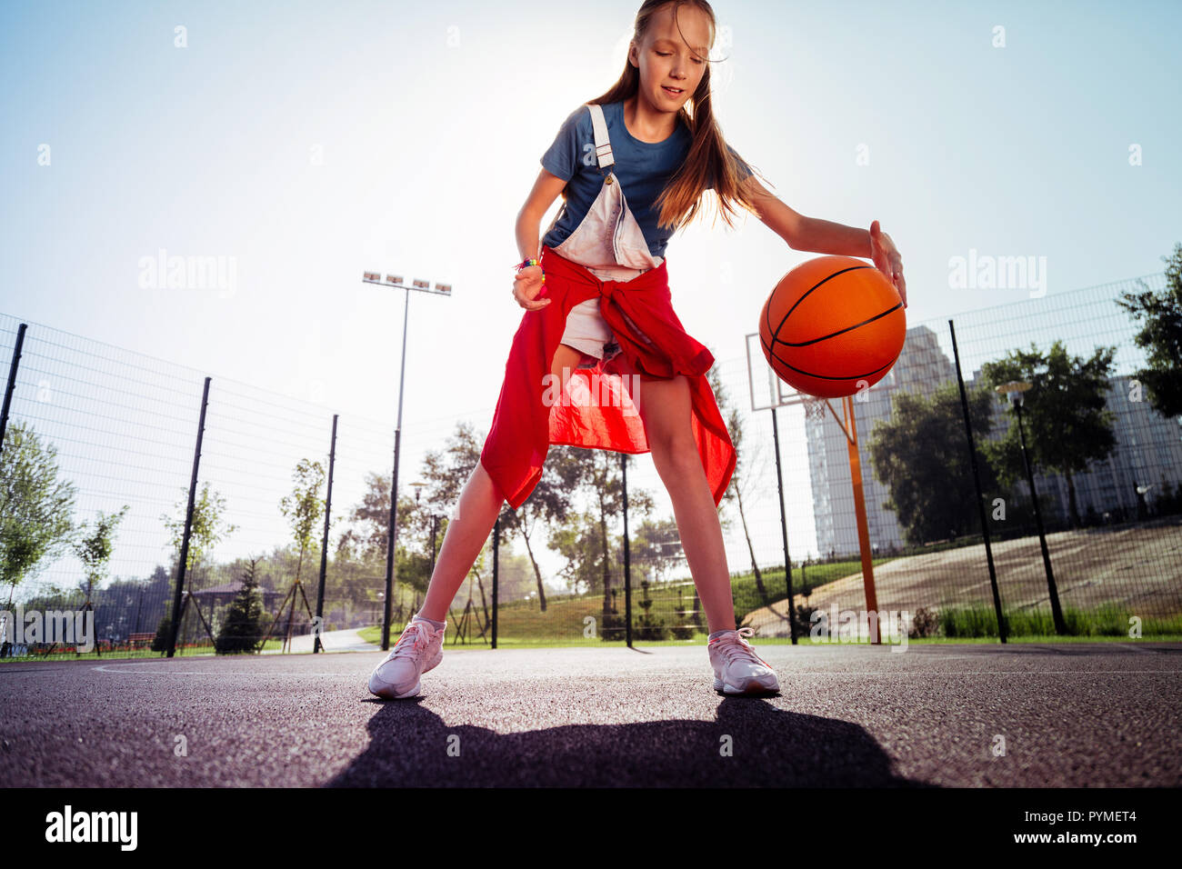 Concentrated little female playing basketball on stadium Stock Photo