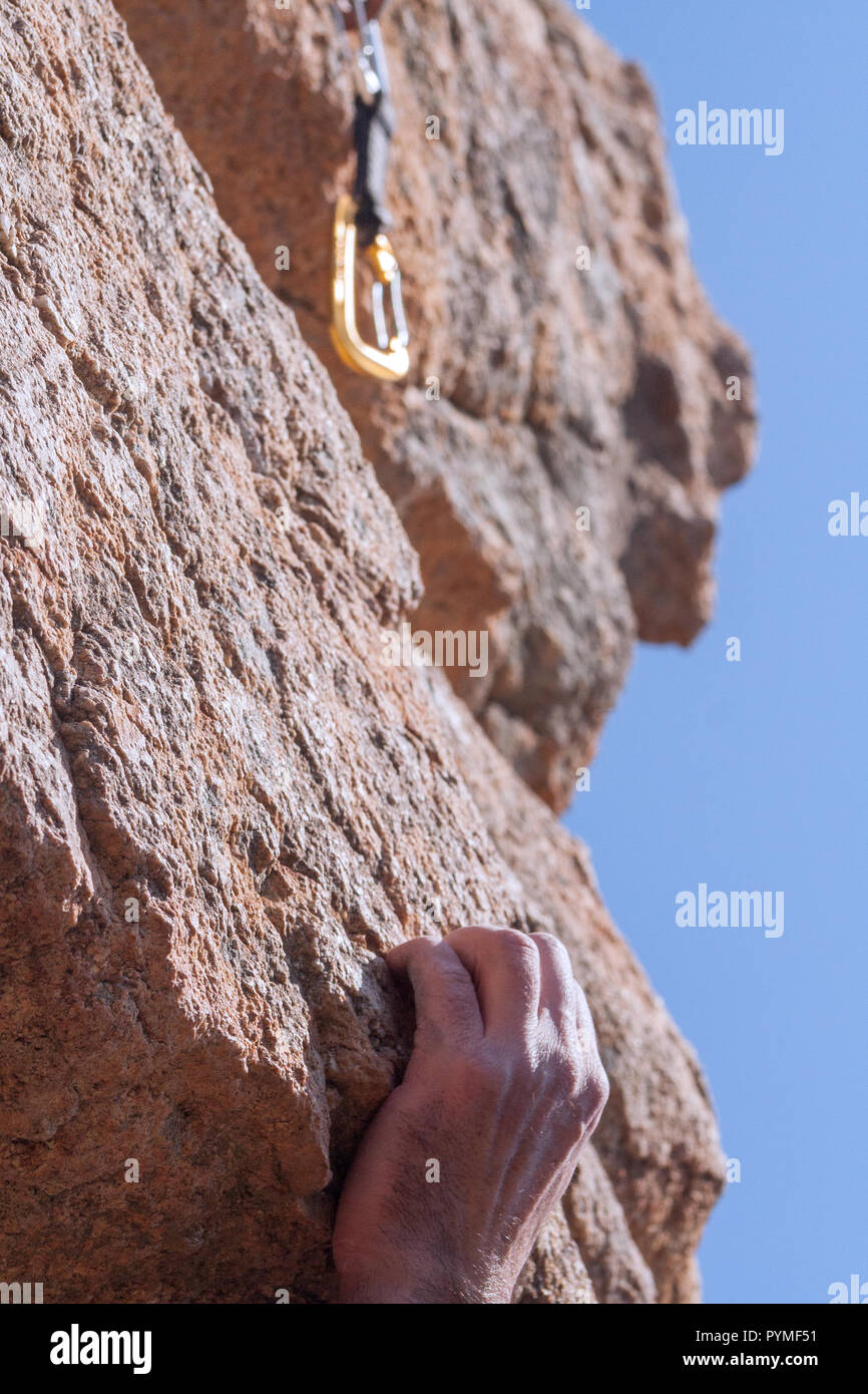Hand of lead climber grabbing a rock with quickdraw on top of him in