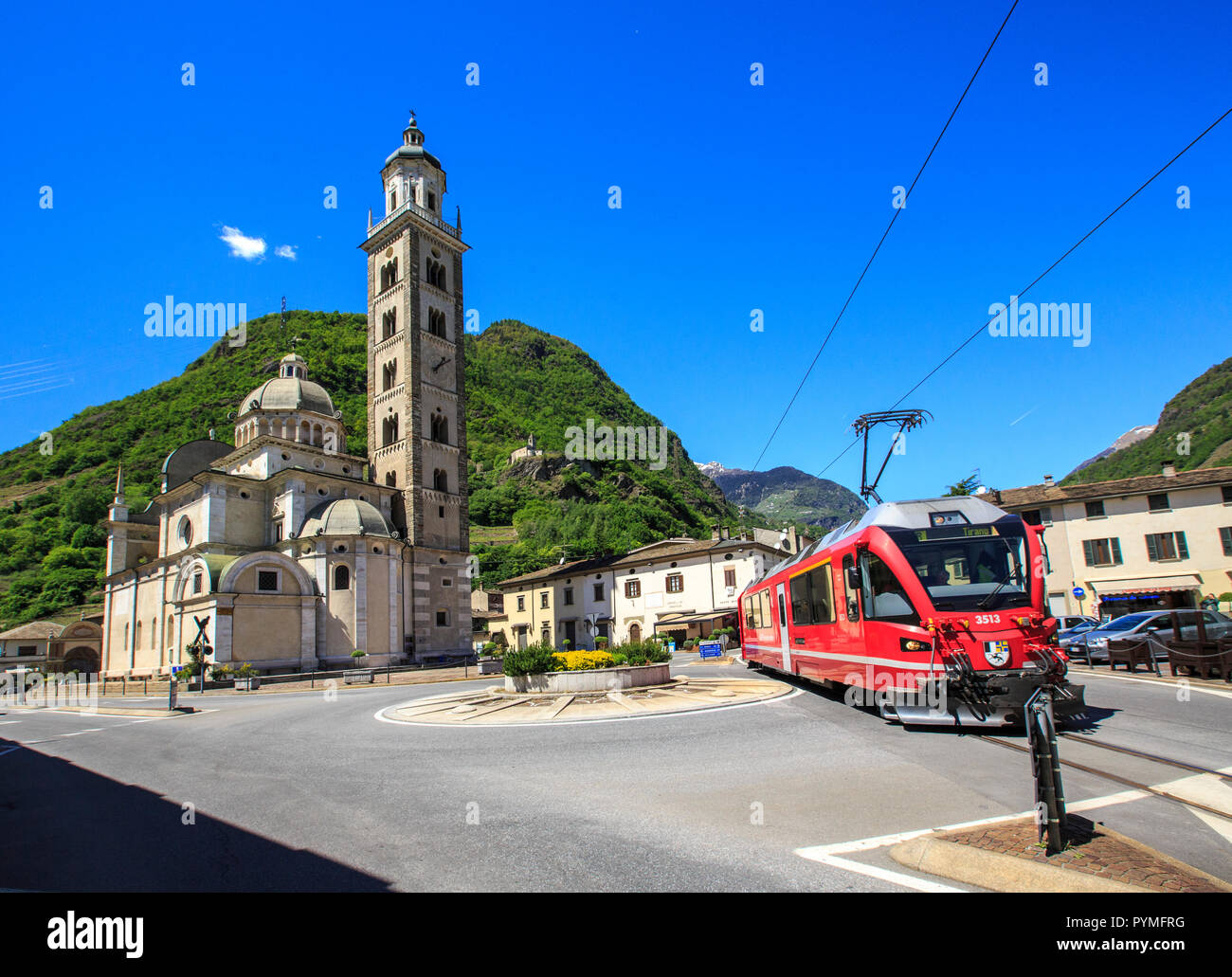 Bernina Express train in transit close to the old sanctuary of Tirano, Valtellina, Lombardy, Italy Stock Photo