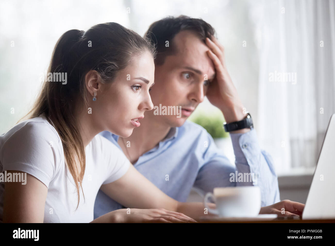 Frustrated surprised spouses looking at computer screen  Stock Photo