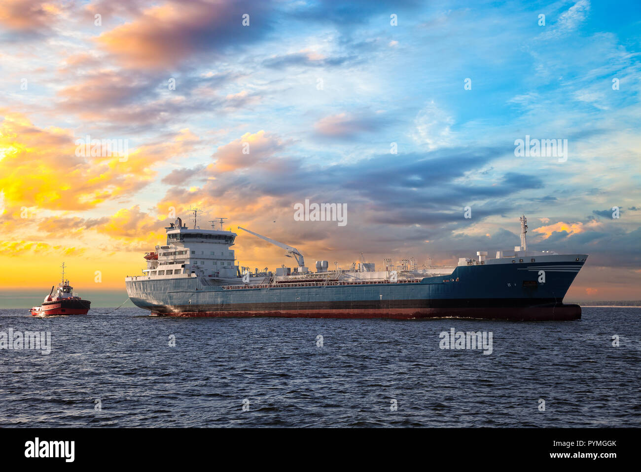 Tanker and tugboat on sea at sunset Stock Photo