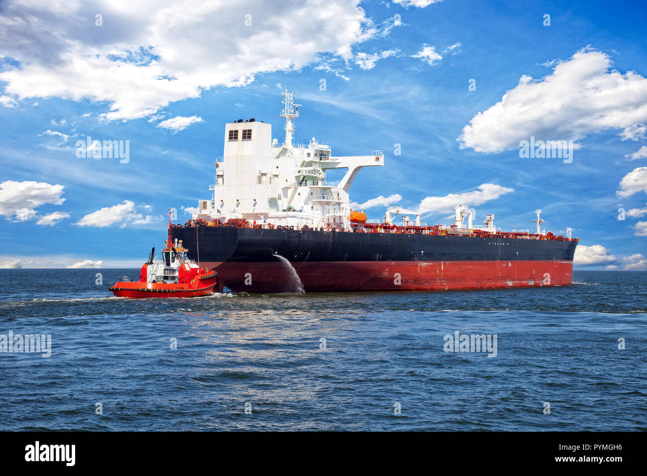 Red tug boat approaching to assist tanker Stock Photo