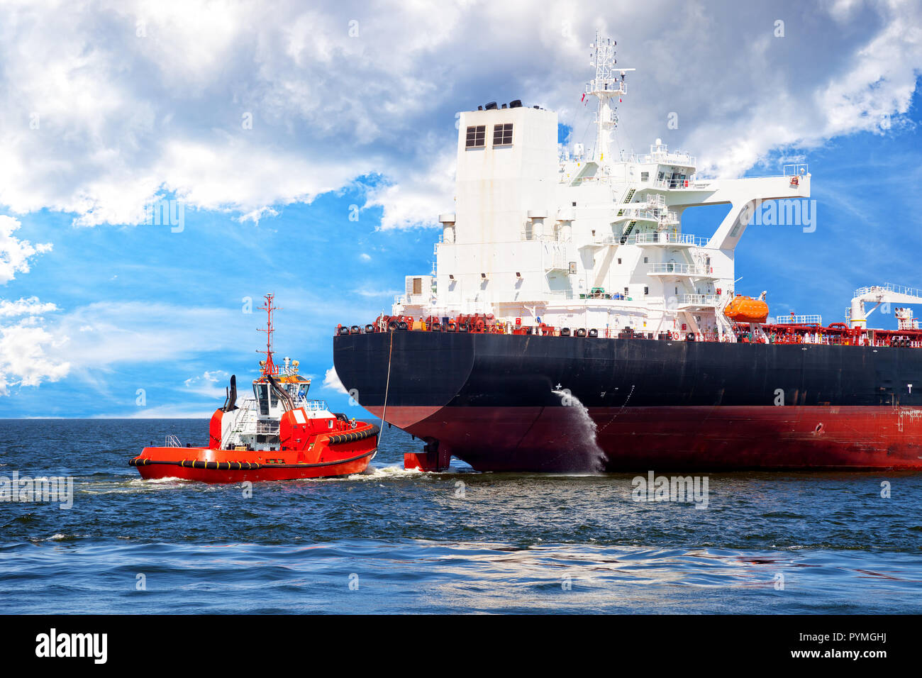 Red tug boat approaching to assist tanker Stock Photo