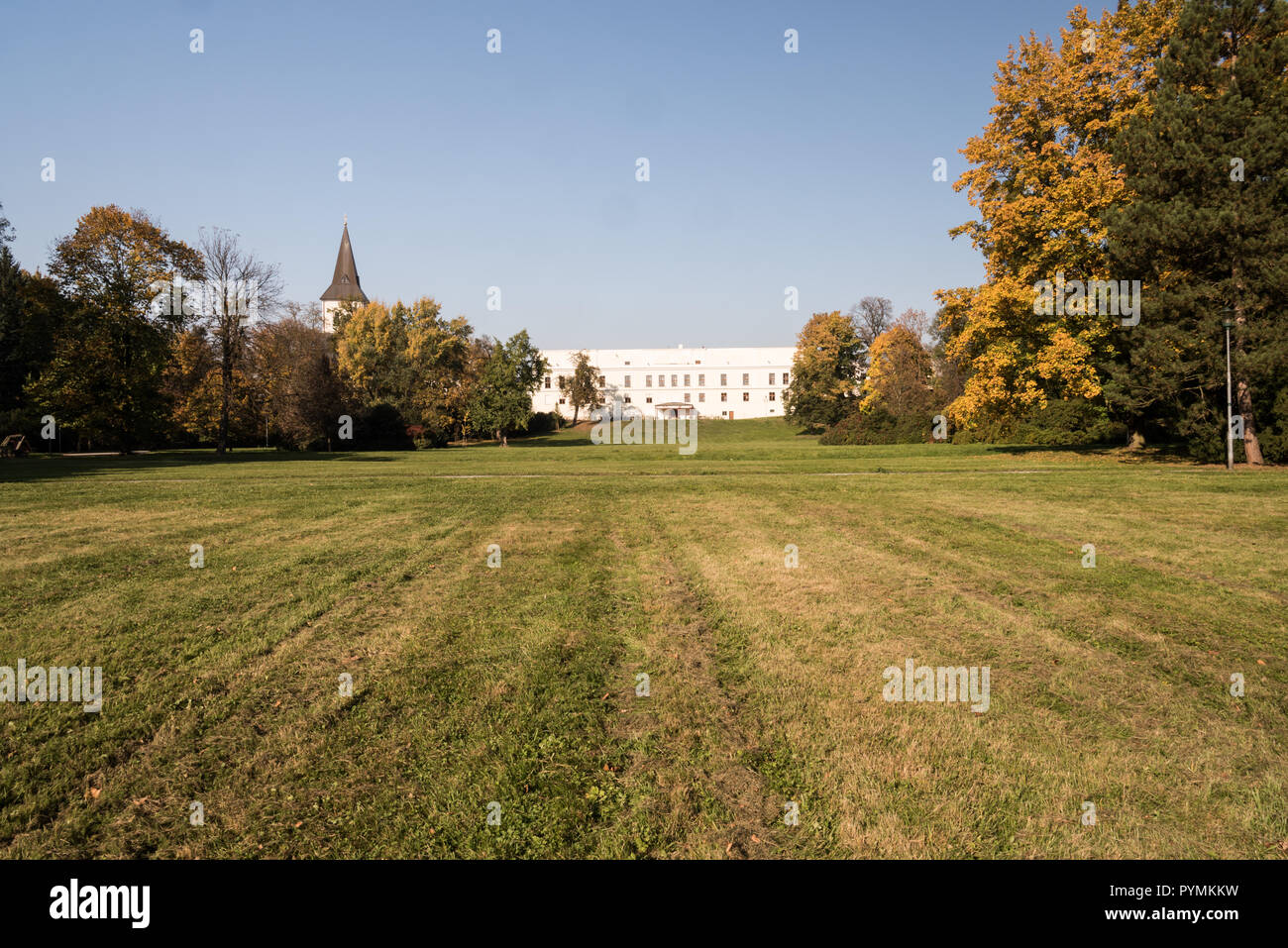 Park Bozeny Nemcove wth grass and colorful trees, chateau Frystat and Kostel Povyseni sv. Krize church on the background in Karvina city during autumn Stock Photo