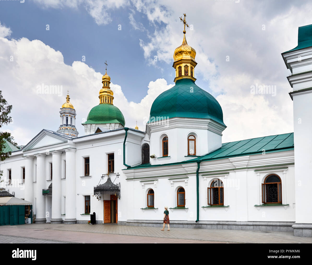 Woman in hat walking near Church with golden domes at Kiev Pechersk Lavra Christian complex. Old historical architecture in Kiev, Ukraine Stock Photo