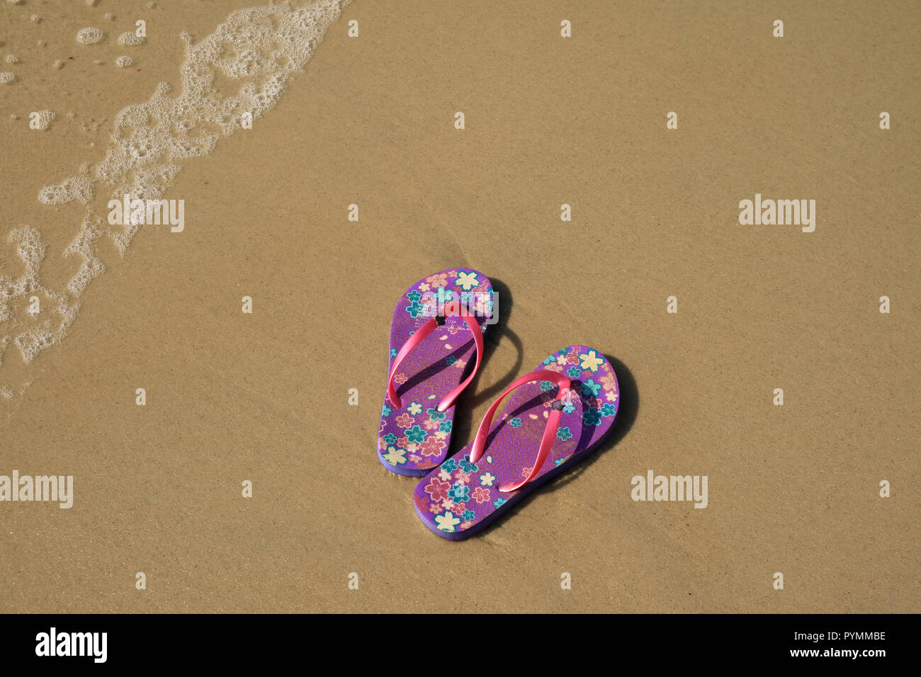 A pair of vibrant purple flip-flops sandals on the sandy beach with the  wave swash, Copacabana beach, Brazil Stock Photo - Alamy