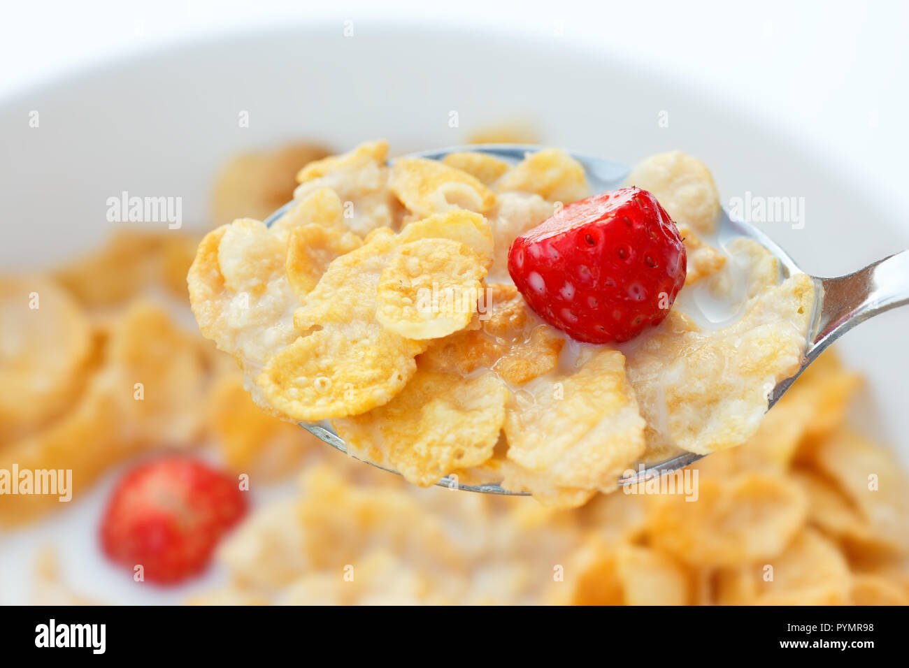Corn flakes, milk, strawberries and spoon Stock Photo