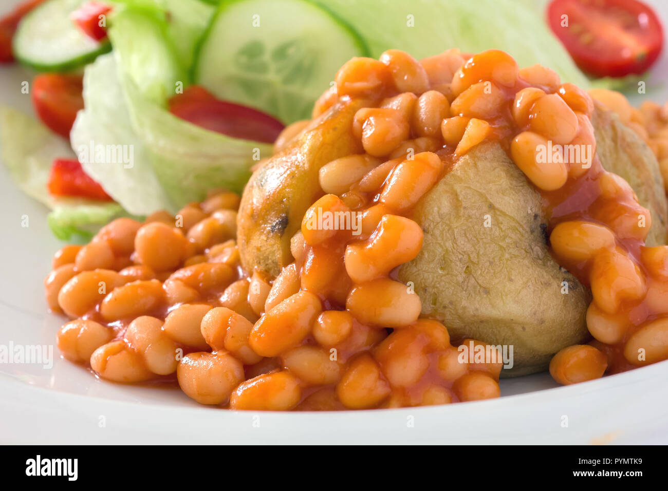 Detail of a jacket potato with baked beans and a out of focus salad