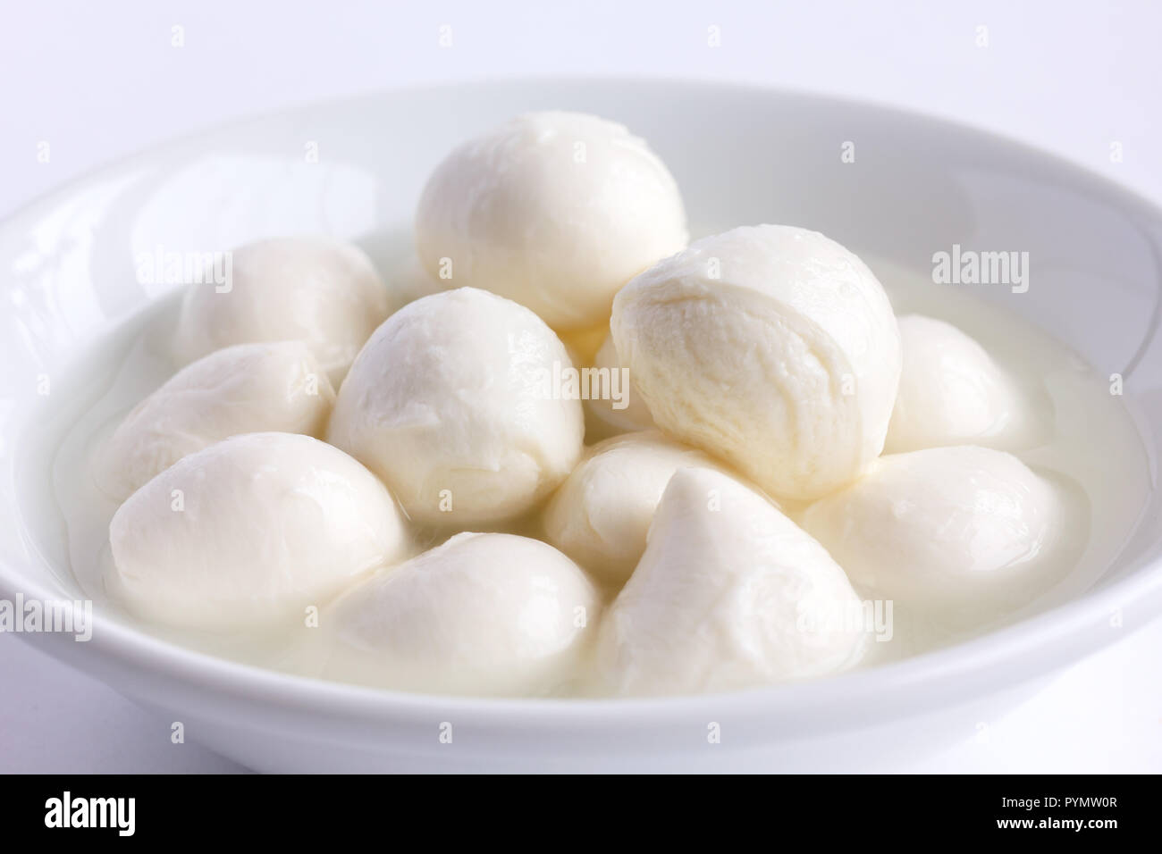 Small white mozzarella balls in a white dish with liquid. Stock Photo